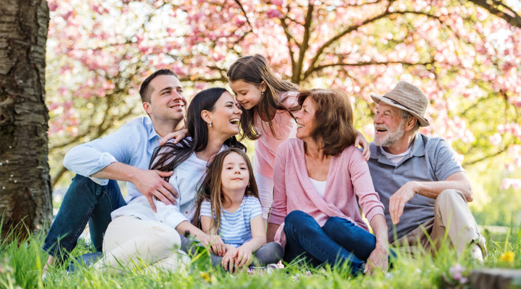 three-generation-family-sitting-outside-in-spring-nature