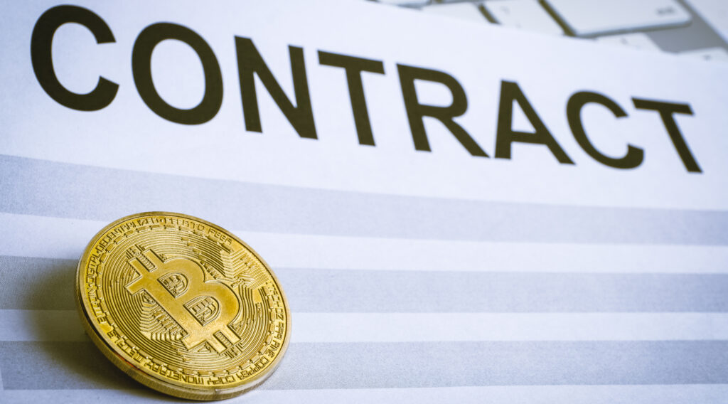 the-concept-of-a-contract-for-the-sale-of-cryptocurrency-bitcoin-coin-on-the-contract-sheet-with-the-keyboard